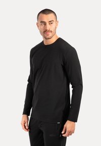 Czarna long-sleeve koszulka wykonana z miękkiej bawełny, z okrągłym dekoltem i regularnym krojem. Gładka tekstura, minimalistyczny design bez wzorów.