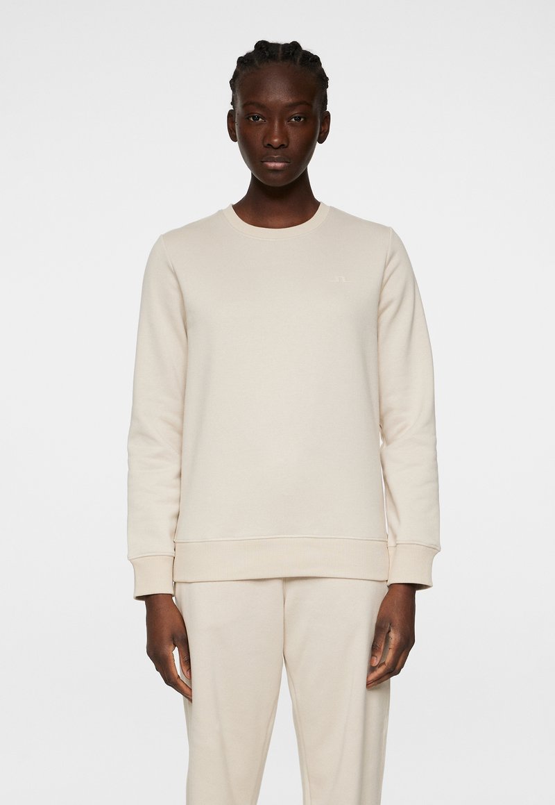 Crème-kleurige sweatshirt met een klassieke ronde hals, ribgebreide mouwen en zoom, gemaakt van zachte stof. Beschikt over een subtiele logo op de borst.