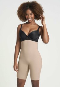 Lichaamsvormende kleding met een zachte zwarte top en een naadloze huidkleurige onderkant. Het reikt tot halverwege de bovenbenen met een aansluitend ontwerp.