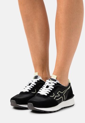 Baskets noires avec une texture en daim, lacets blancs et une accentuation contrastante de couleur claire. Semelle rembourrée avec un fond en caoutchouc texturé.