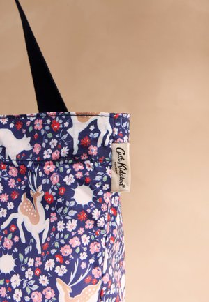 Nagy táska sötétkék anyagból, fehér és barna szarvasmintákkal, rózsaszín és piros virágokkal, valamint bézs "Cath Kidston London" felirattal.