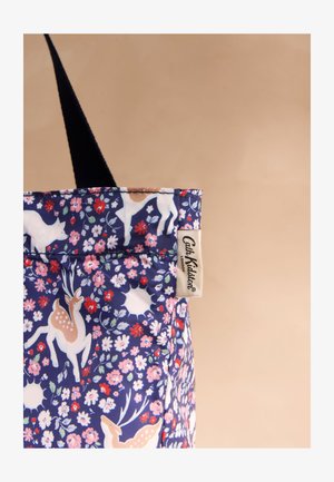 Geantă tote din material bleumarin cu modele de cerbi albi și maro, flori roz și roșii și o etichetă bej "Cath Kidston London".