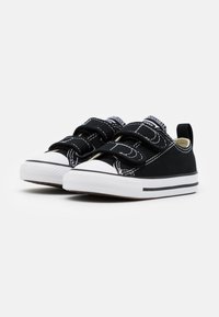 Sneakers in tela nera con doppie fascette in Velcro, punte in gomma bianca e dettagli di cucitura a contrasto. Suola intermedia bianca con striscia nera.