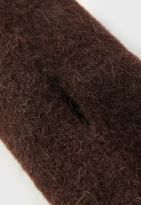 Brun, teksturert ullstoff med en myk, lodden overflate og en liten spalte detalj. Tette fibre gir et rikt utseende.