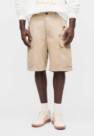 Μπεζ cargo σορτς από ελαφρύ ύφασμα με πολλαπλές πλαϊνές τσέπες, άνετη εφαρμογή και σχέδιο με τελείωμα πάνω από το γόνατο.