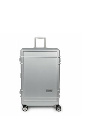 Maleta plateada de carcasa rígida con cuatro ruedas y asa extendida, de diseño rectangular y logotipo de Eastpak en la parte delantera.