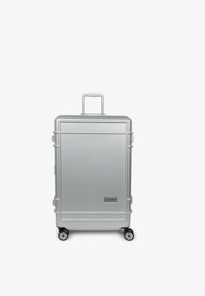 Maleta plateada de carcasa rígida con cuatro ruedas y asa extendida, de diseño rectangular y logotipo de Eastpak en la parte delantera.