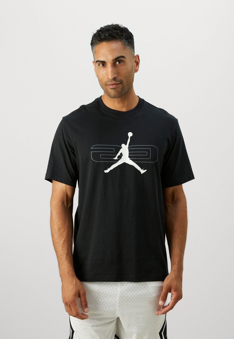 Sort bomulds t-shirt med et stort hvidt Jumpman-logo på brystet, rund hals og korte ærmer. Stoffet har en glat tekstur.