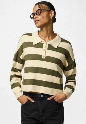 Zelený a smetanový pruhovaný pletený svetr s límcem a zapínáním na knoflíky, s volnějším střihem a žebrovanými manžetami. Nosený s černými kalhotami.