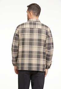Geruite shirt in beige en grijstinten; geweven stof, knoopmanchetten en een standaard kraag. Heeft een yoke en zichtbare stikseldetails.