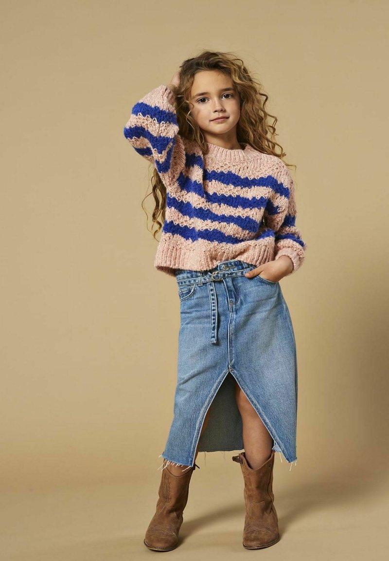 Strikket pink og blå stribet sweater, denimnederdel med frynset kant og frontendspalte, brune cowboystøvler. Enkel, afslappet outfit med tekstur.