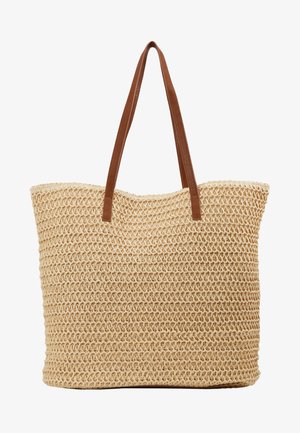 Austiņas no vītā salmiem ar cilindrisku formu, gaiši bēša krāsa, tekstūras virsma un brūnas mākslīgās ādas siksnas.