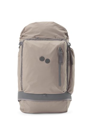 Beiger und grauer Rucksack mit vorderer Reißverschlusstasche, zwei runden schwarzen Logopunkten, gepolstertem Boden und Seitenfächern.