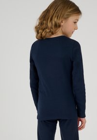 Top de manga larga de rayas en color navy con cuello redondo y dobladillo recto. Textura suave, diseño ajustado y hombros sin costuras.