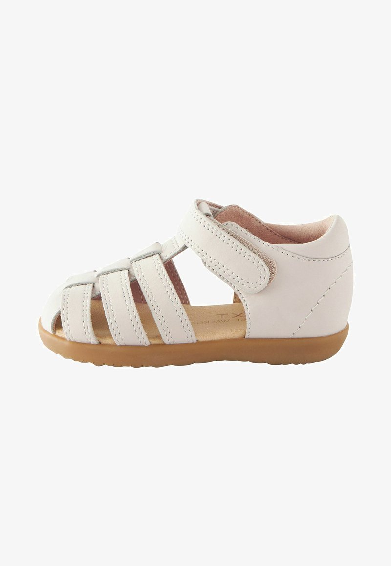 Witte leren sandaal met open teen, meerdere banden en klittenbandsluiting. Textuur van een lichtbruine zool. Minimalistisch ontwerp, platte profiel.