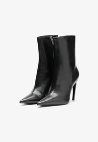 Stivaletti neri in pelle, con punta affusolata, superficie liscia, chiusura con zip e tacco a stiletto. Progettati per una silhouette aderente.
