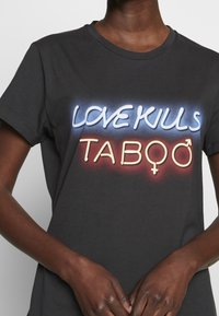 Černé bavlněné tričko s krátkým rukávem, které zobrazuje neonový nápis: "LOVE KILLS" v modré barvě a "TABOO" v žluté barvě, se symboly pro muže a ženy.