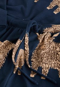 Marineblauwe stof met beige dierenpatronen, voorzien van een trekkoordsluiting en een textuur met gebreide oppervlakte. Zacht en comfortabele ontwerp.