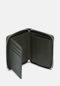 Skórzany portfel w ciemnozielonym kolorze, wyposażony w zamek błyskawiczny, liczne przegródki na karty oraz gładką teksturę. Wewnątrz znajdują się sekcje na dowody tożsamości i karty.