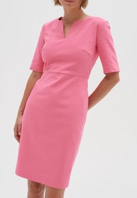 Fitted rosa klänning med korta ärmar, V-ringning och sidficka. Slät textur, knälång design med subtila sömdetaljer.