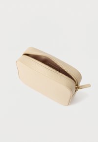 Smėlio spalvos odinis krepšelis su tekstūruotu paviršiumi, išlenkta forma ir auksiniu užtrauktuku. Viduje rudos spalvos pamušalas. Kompaktiškas dizainas patogiam laikymui.