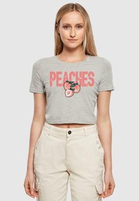 Pilkas trumpas marškinėliai su žodžiu "PEACHES" rožine spalva ir persiko grafika apačioje. Pagaminti iš minkštos medvilnės, skirti kasdieniam dėvėjimui.