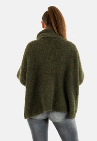 Olijfgroen oversized sweater met een hoge kraag, textuurstof en verlaagde schouders. De achterkant heeft een eenvoudige naad in het midden.