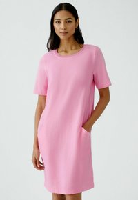 Kurzes pinkes Kleid mit kurzen Ärmeln, Rundhalsausschnitt und seitlichen Taschen. Hergestellt aus einem strukturierten Stoff, bietet es eine lockere Passform und ein einfaches Design.