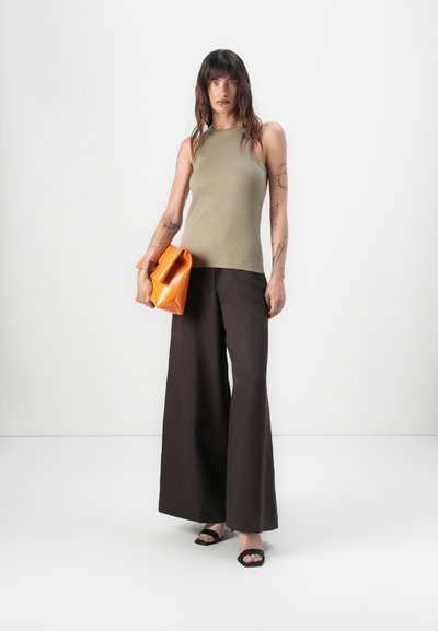 Top sin mangas de color verde oliva, pantalones de pierna ancha marrones y zapatos de verano negros de punta abierta. Bolso naranja con un diseño estructurado y una textura suave.