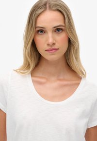 Hvid bomulds T-shirt med rund halsudskæring og korte ærmer. Har et subtilt logo på venstre side. Blød og let tekstur.