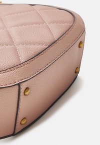Borsa a tracolla in pelle rosa con texture trapuntata, forma arrotondata, dettagli scuri sui bordi e borchie color oro. La superficie appare leggermente granellata.