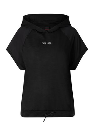 Kobieta w czapce z daszkiem, luźnej czarnej bluzie z krótkim rękawem i kapturem, czarnych spodenkach kolarskich i czarnych sandałach, stojąca na jednolitym jasnym tle.