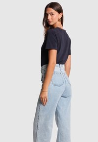 Camiseta azul marino de manga corta combinada con jeans de mezclilla de cintura alta en un tono azul claro, con un corte relajado y bolsillos traseros.