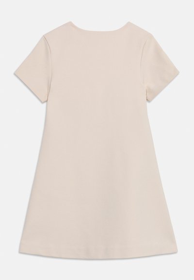 Απλό μπεζ φόρεμα με κοντά μανίκια και στρογγυλή λαιμόκοψη, εμφανιζόμενο από πίσω πάνω σε λευκό φόντο.