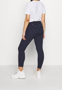 Marina leggings med en figurnära design, tillverkade av ett elastiskt material. Har en hög midja och två bakfickor med kontrasterande kant.