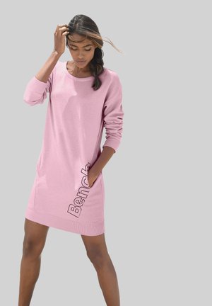Roze sweatshirtjurk van zachte stof, met lange mouwen, een ronde hals en zijzakken. "Bench" logo langs de zijkant weergegeven.