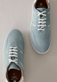 Baskets en suède bleu clair avec des lacets blancs et des semelles en caoutchouc blanches. Présentent des accents perforés et un intérieur en cuir lisse.