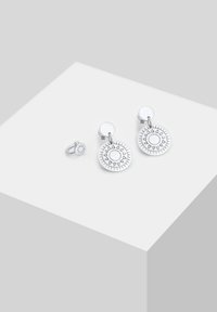 Ensemble de boucles d'oreilles en argent présentant des designs circulaires avec des motifs solaires, comprenant une paire de boucles d'oreilles pendantes et une petite puce.