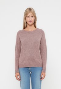 Ribbete crew-neck genser i myk mauve stoff. Har lange ermer og en avslappet passform, sammen med lyseblå jeans.