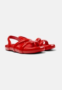 Red plastic sandals featuring a smooth, glossy finish, with cutout details and a molded design for comfort and breathability.