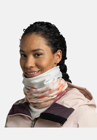 Multicolored neck gaiter in soft fabric, featuring a swirling pattern of orange and pink with a white base. Worn layered over a light jacket.