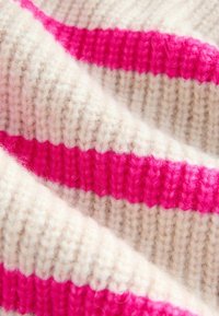 Strikket stof i beige og lys pink. Blød tekstur med skiftende brede striber, der fremhæver det kontrasterende farvemønster.