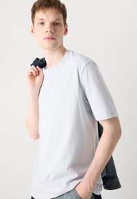 Light gray short-sleeve t-shirt made of soft fabric, featuring a simple design and a subtle logo detail on the chest.