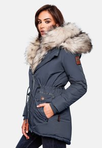 Parka isolante bleu foncé avec capuche en fourrure, taille à cordon, poches multiples et un écusson de marque sur la manche.