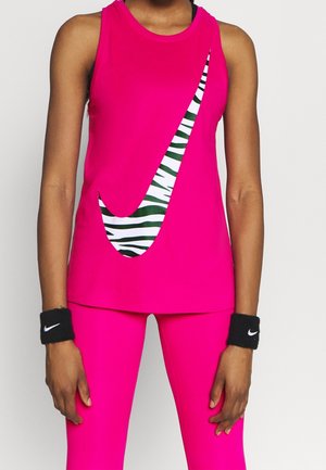 Personne portant une tenue de sport rose vif avec un grand swoosh Nike zébré sur le haut et des bracelets noirs avec des logos Nike blancs.