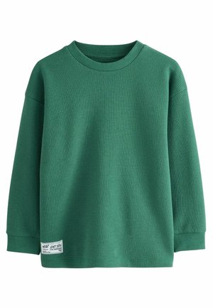 Grünes Langarmshirt aus strukturiertem, geripptem Material. Rundhalsdesign mit einem Etikett auf der linken unteren Seite. Weite Passform.