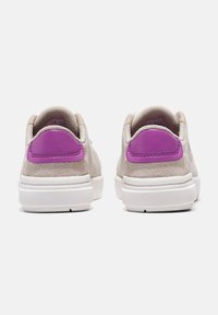 Sneakers i beige mockasinläder med lila läderaccent på hälen. Vit gummisula, rund tå och minimalistisk design med stickade detaljer.