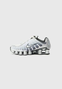 Nike running shoe featuring a white and silver design, a textured upper, prominent side fins, and a distinctive cushioned sole.