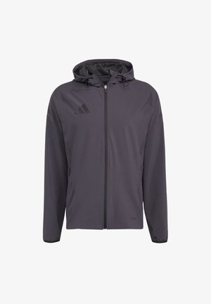 Jachetă ușoară gri cu glugă, fermoar frontal și șnururi. Prezintă logo-ul Adidas în negru în partea superioară stângă. Material neted, rezistent la apă.
