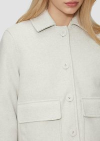 Manteau en laine gris clair avec un col classique, quatre grands boutons et deux poches avant à rabat. Texture douce avec un design épuré.
